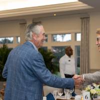 Two gentleman at event smiling and shaking hands